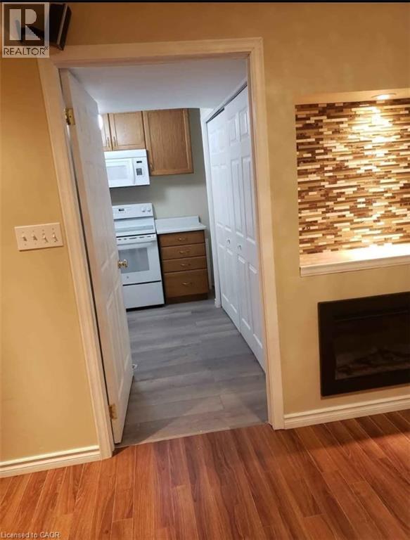 A kitchen with a white oven and microwave, wooden cabinets, and a fireplace.