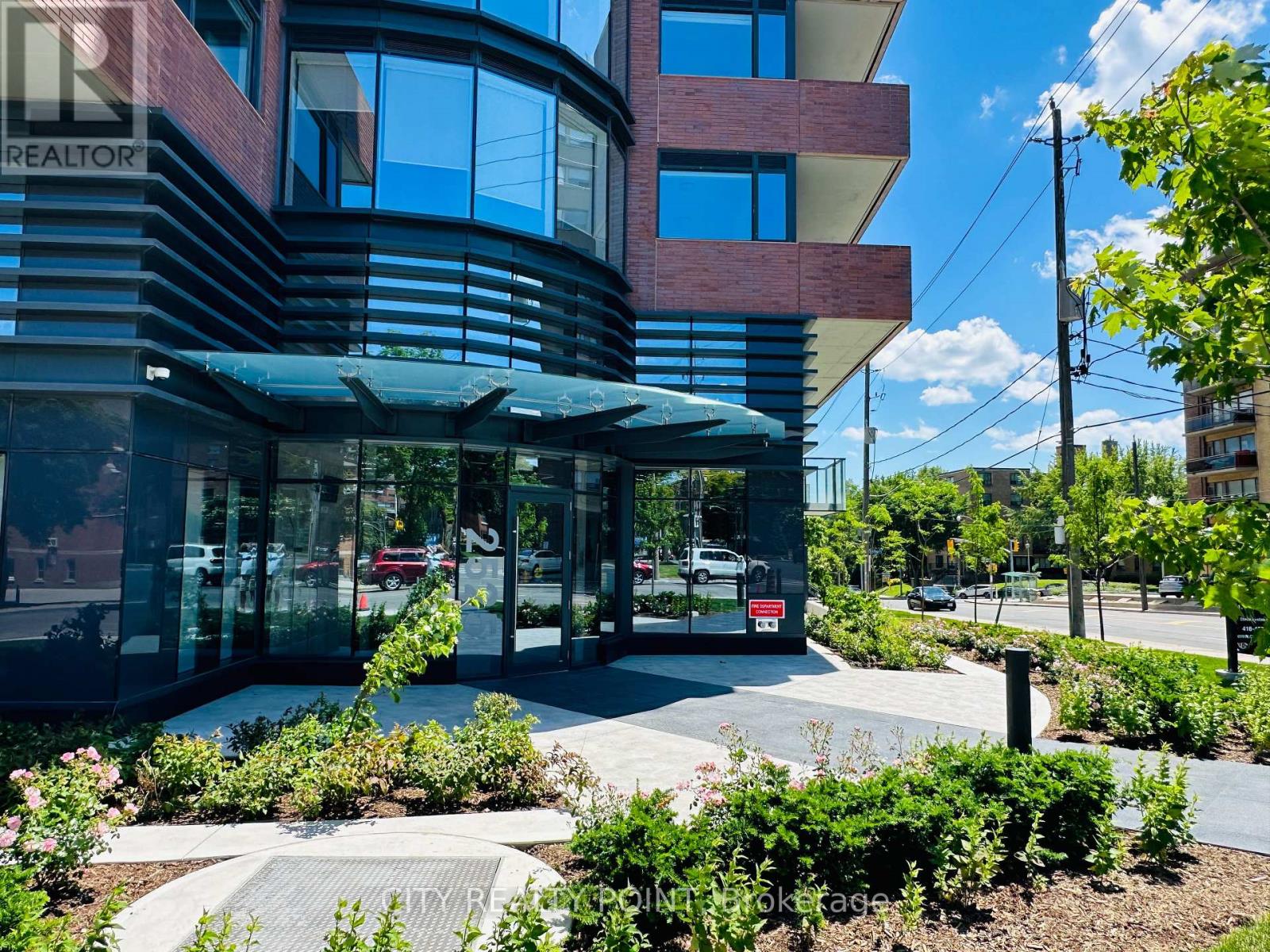 A modern building with a glass entrance and a landscaped area in front.