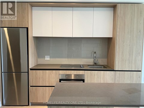 A modern kitchen with wooden cabinets and a stainless steel refrigerator.