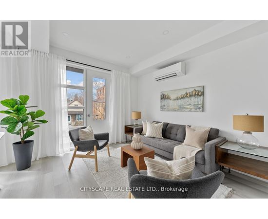 A living room with a grey couch, a wooden table, and a painting on the wall.