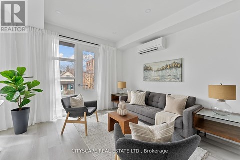 A living room with a grey couch, a wooden table, and a painting on the wall.