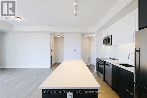 A modern kitchen with black cabinets and stainless steel appliances.