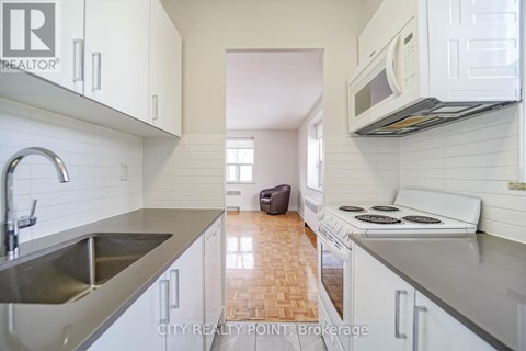 A kitchen with white cabinets and a stove top oven.