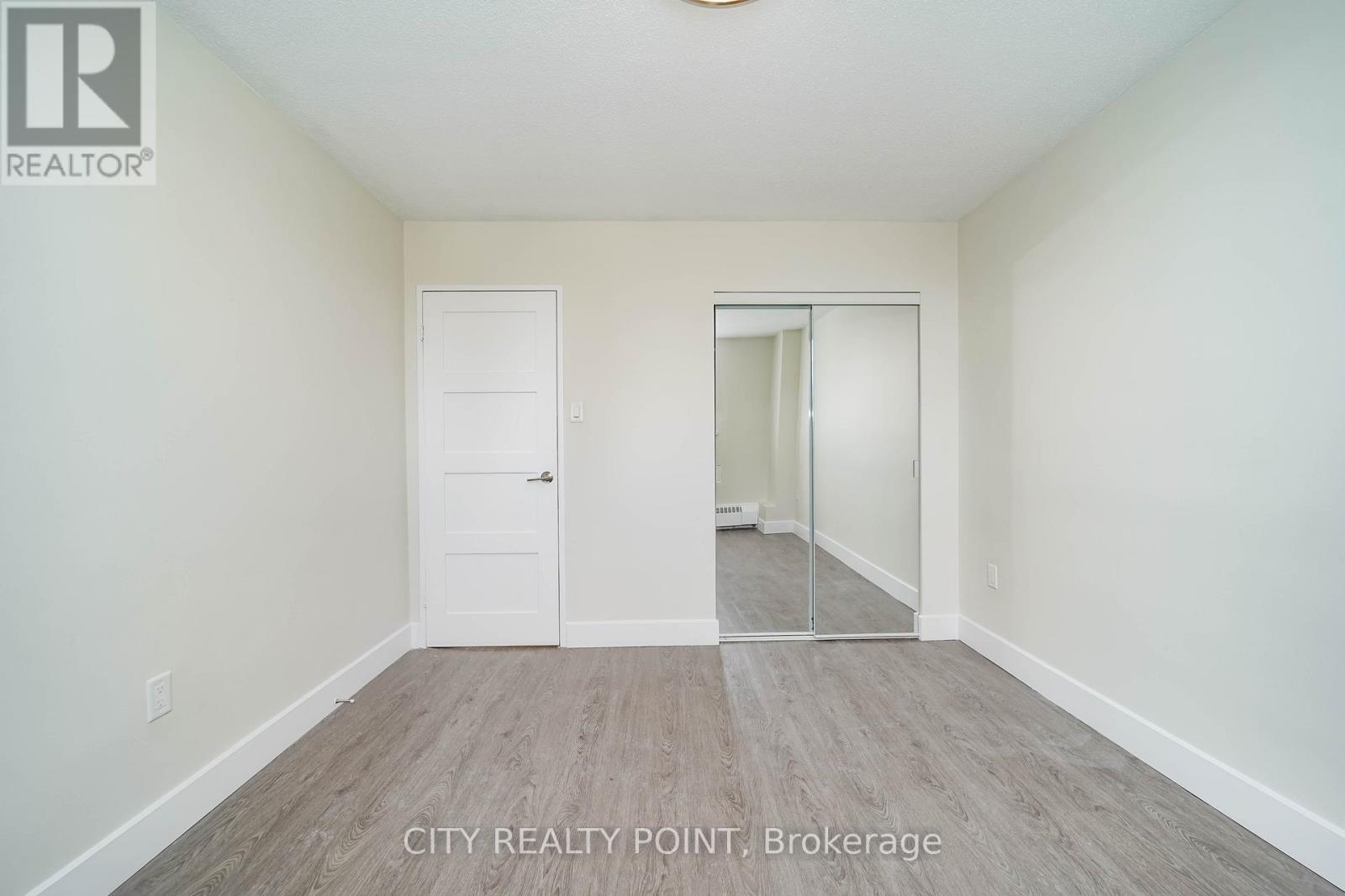 A spacious room with a door and a mirror on the wall.