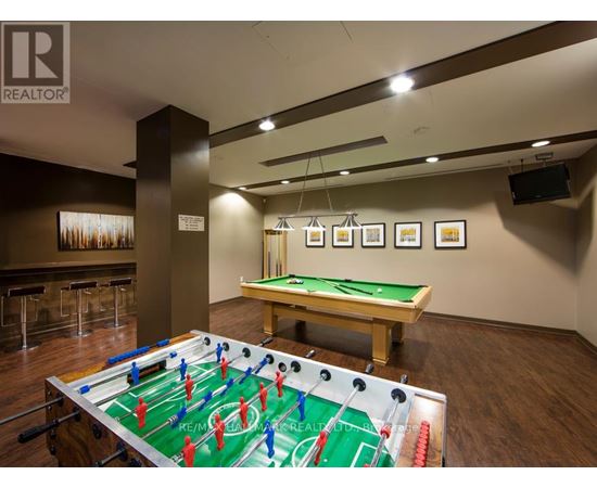 A foosball table is in the middle of a room with a pool table in the background.