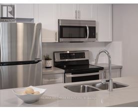 A modern kitchen with a stainless steel refrigerator, microwave, oven, and sink.