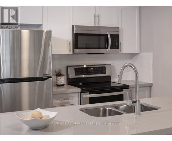A modern kitchen with a stainless steel refrigerator, microwave, oven, and sink.