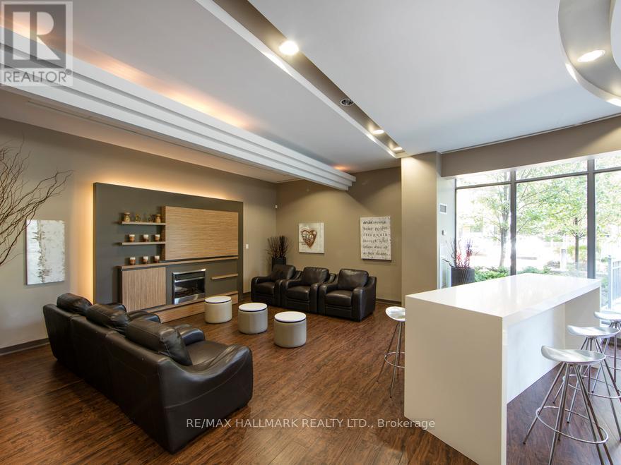 A modern living room with a black leather couch and a white kitchen island.