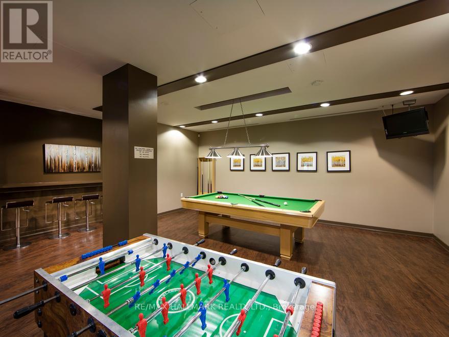 A foosball table is in the middle of a room with a pool table in the background.
