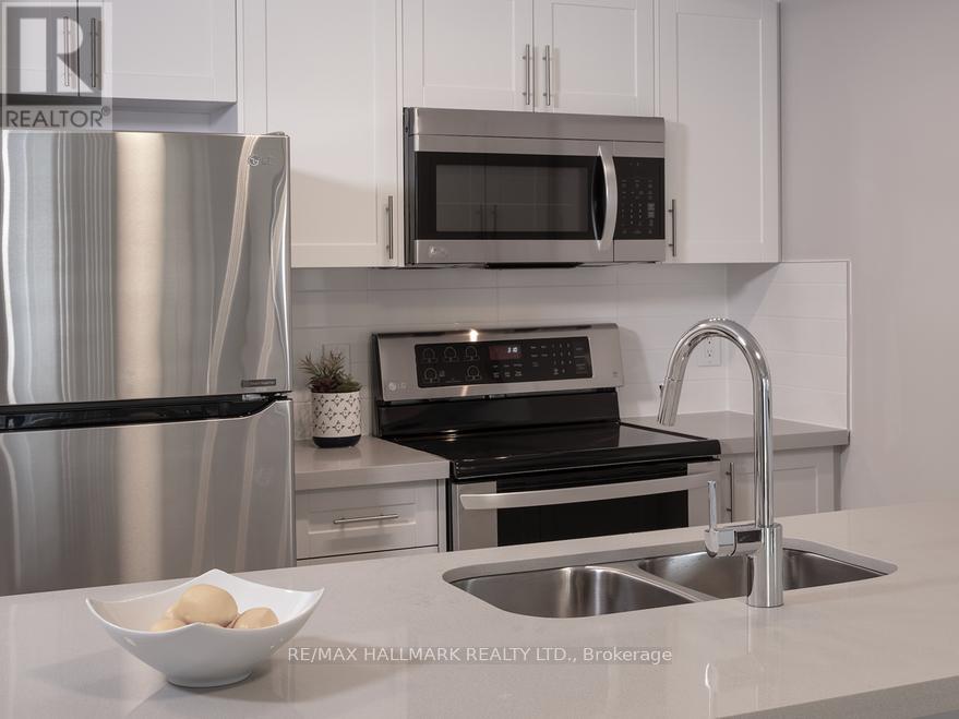 A modern kitchen with a stainless steel refrigerator, microwave, oven, and sink.