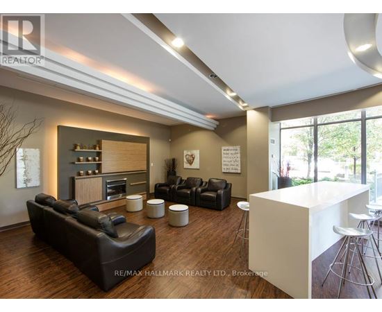 A modern living room with a black leather couch and a white kitchen island.
