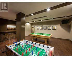 A foosball table is in the middle of a room with a pool table in the background.