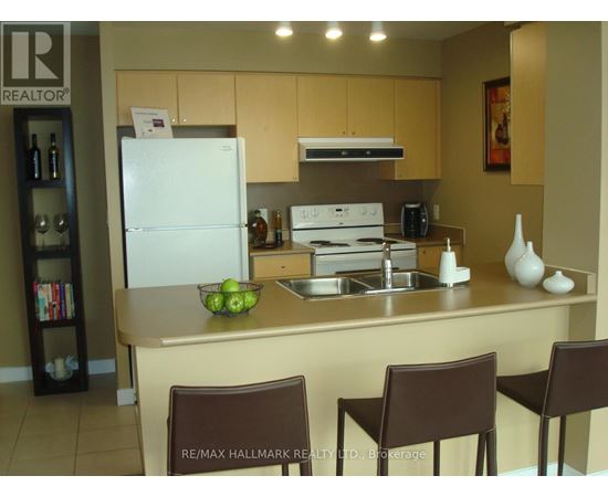 A kitchen with a white fridge, brown chairs and a sink.
