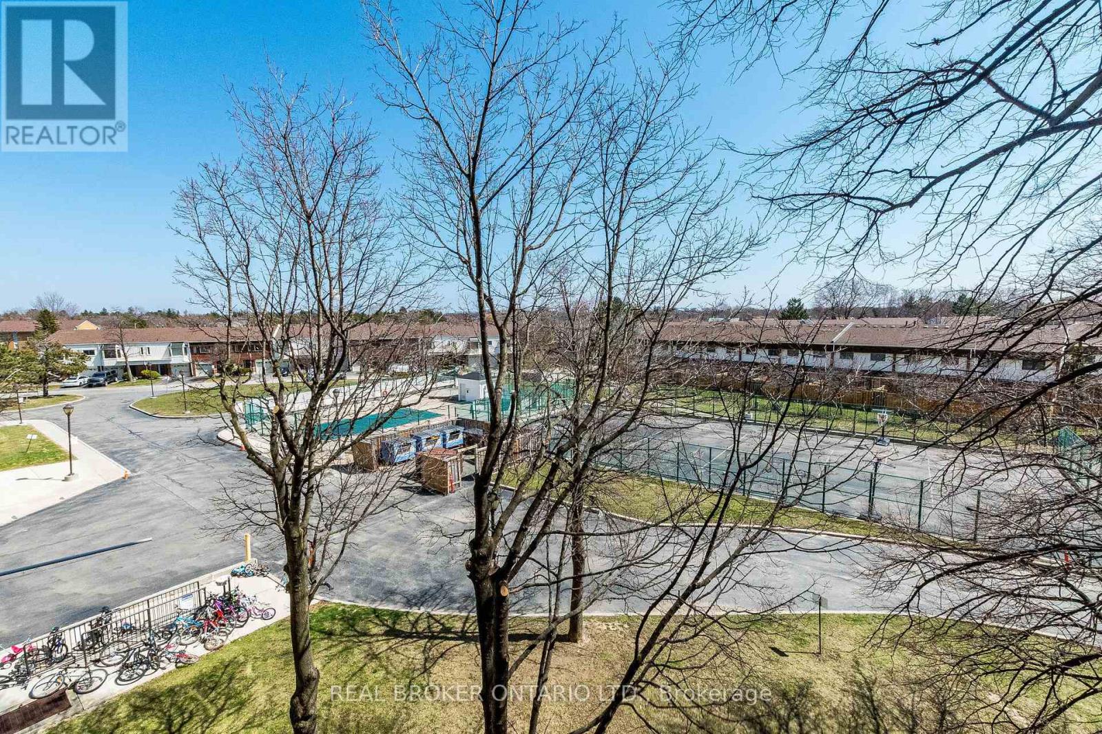 A view of a residential area with a swimming pool and leafless trees.