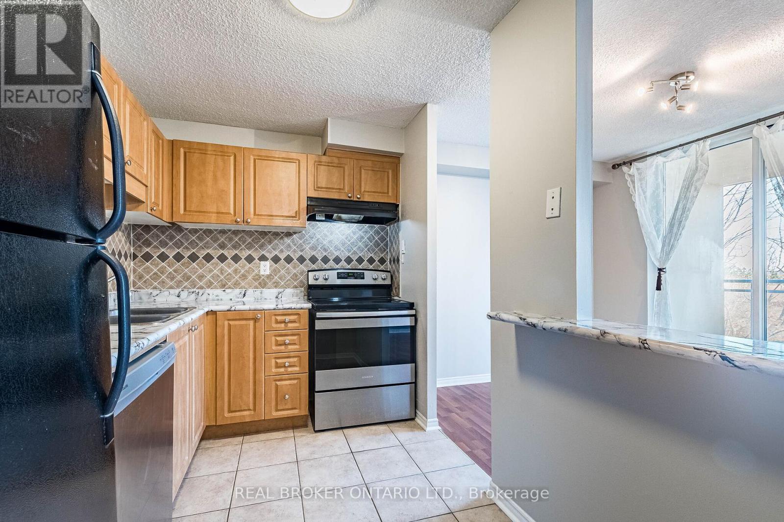 A kitchen with a black fridge, wooden cabinets, and a stove top oven.