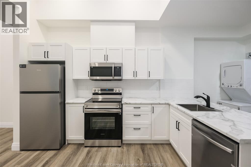 A kitchen with white cabinets and a stainless steel refrigerator.