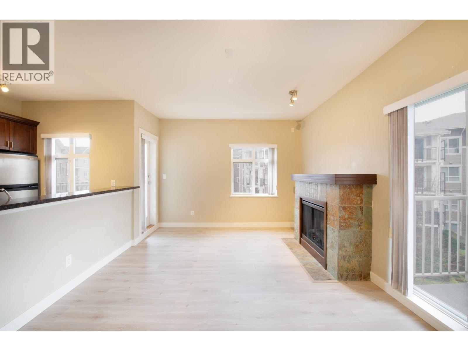 A large, empty living room with a fireplace and a window.
