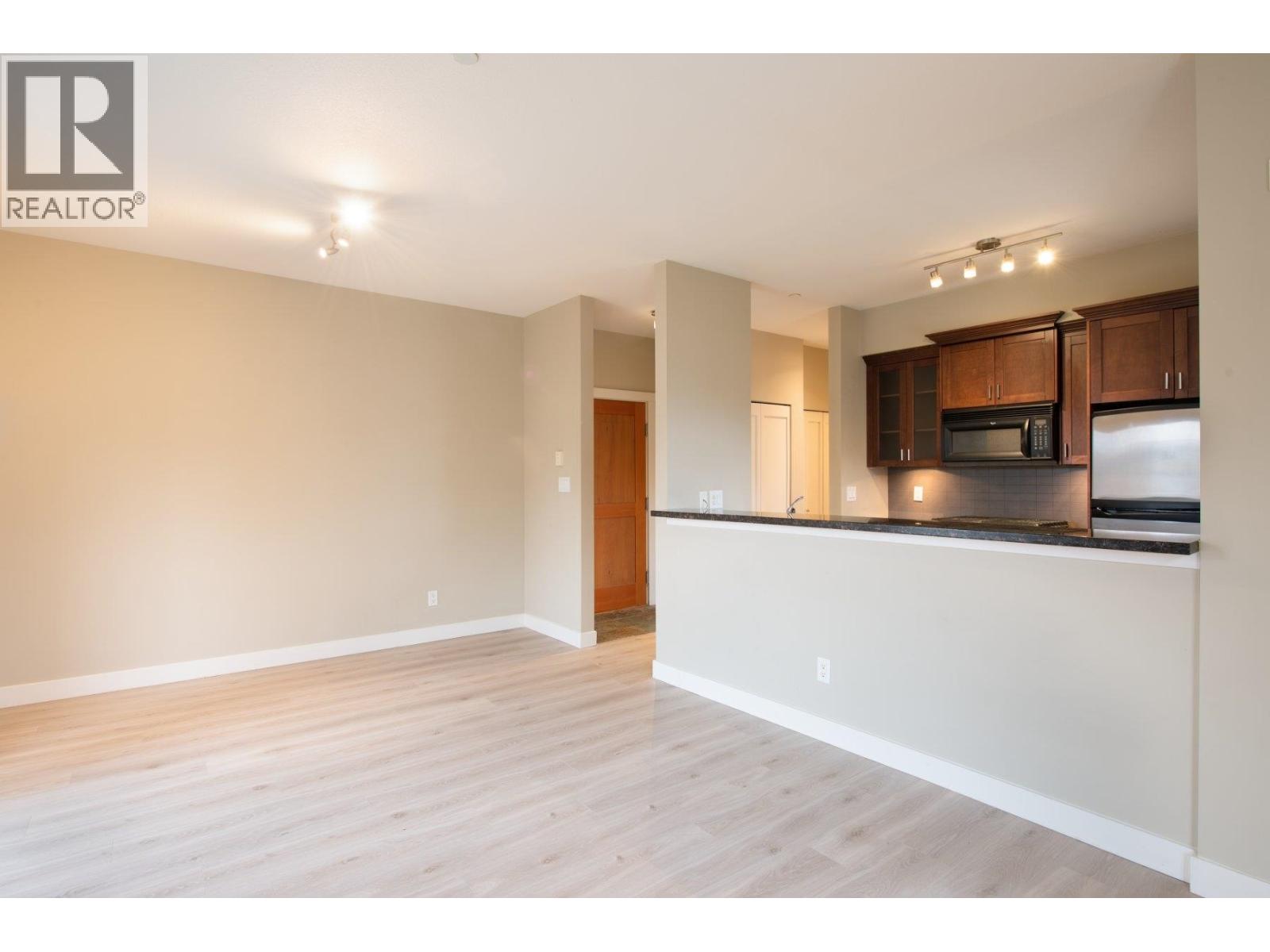 A spacious living room with a kitchen area in the background.