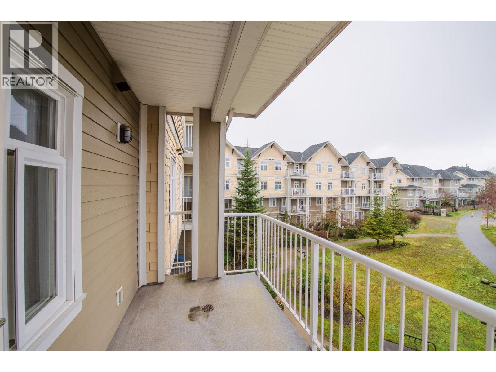 A balcony with a white railing and a view of apartment buildings.
