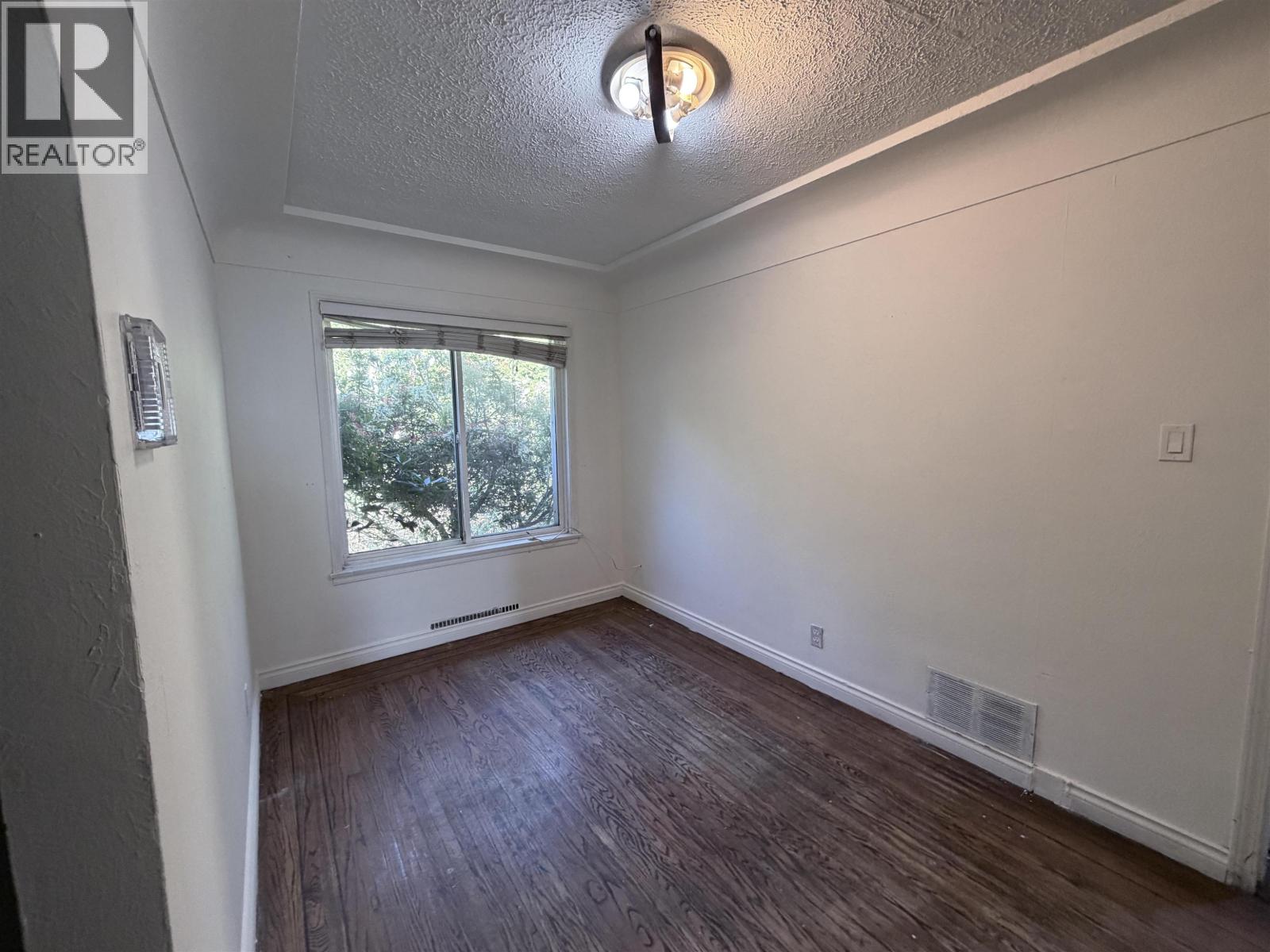 A room with a window and wooden flooring.
