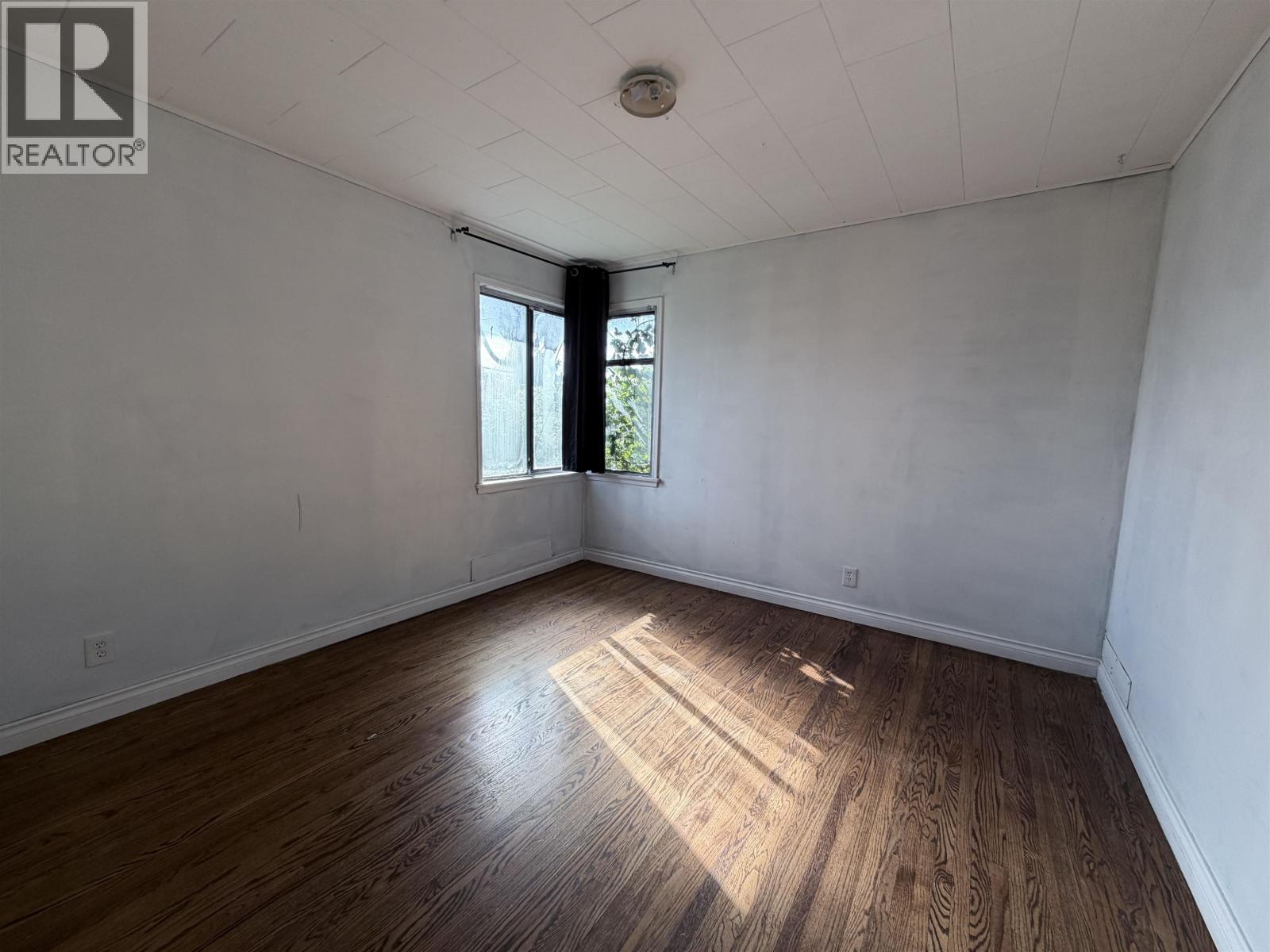 A room with wooden flooring and a window letting in sunlight.