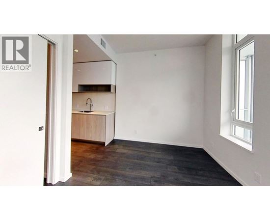 A room with a wooden floor and a window on the right side.