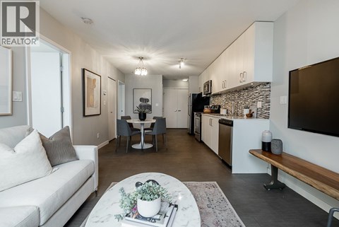 A living room with a white couch and a dining table with chairs.
