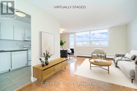 A modern living room with a kitchen area in the background.