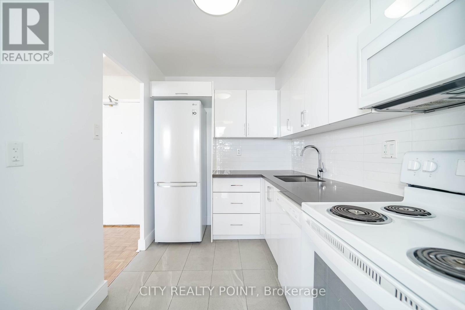 A white kitchen with a refrigerator, stove, and microwave.