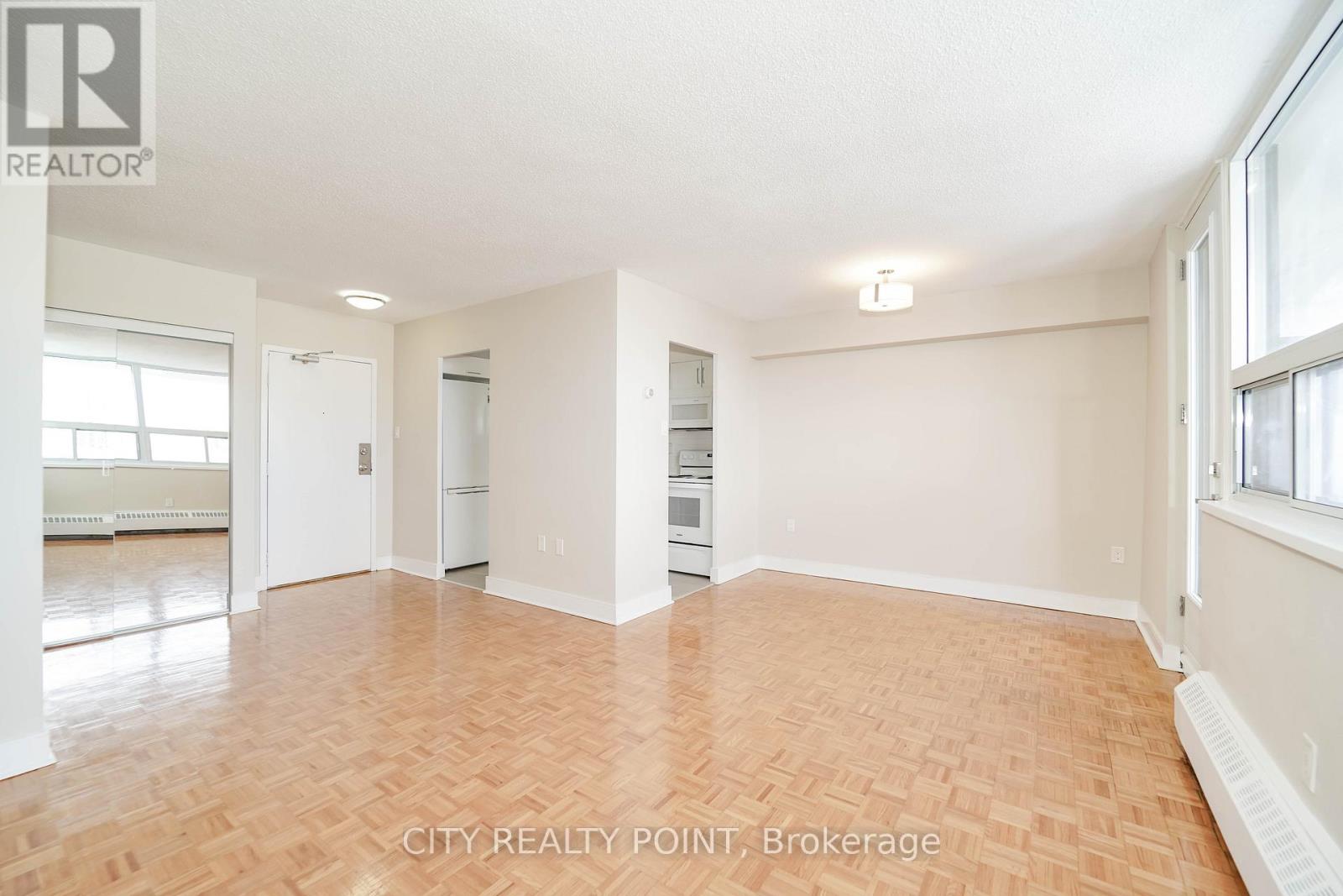 A spacious room with wooden flooring and white walls.