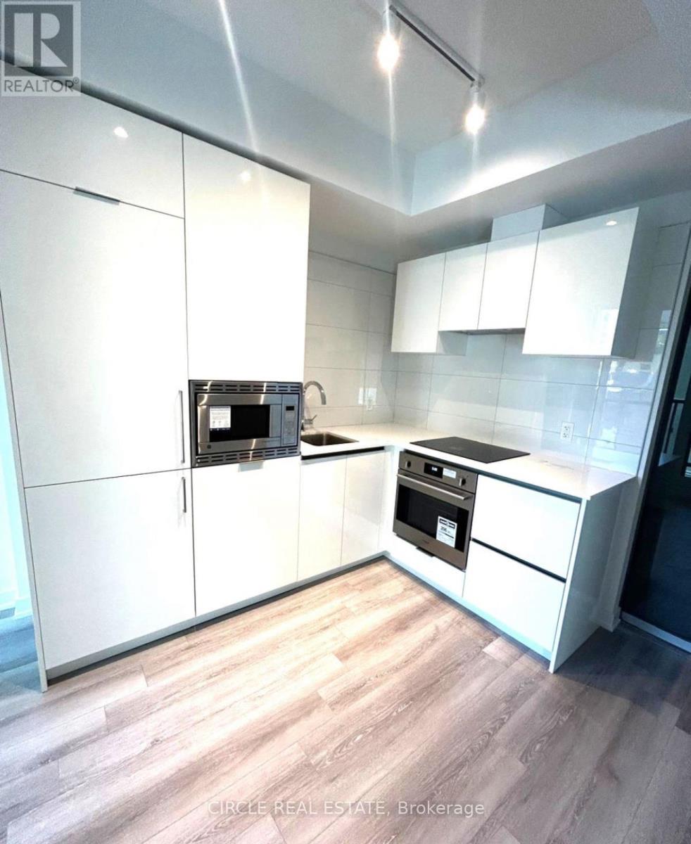 A modern kitchen with white cabinets and a wooden floor.