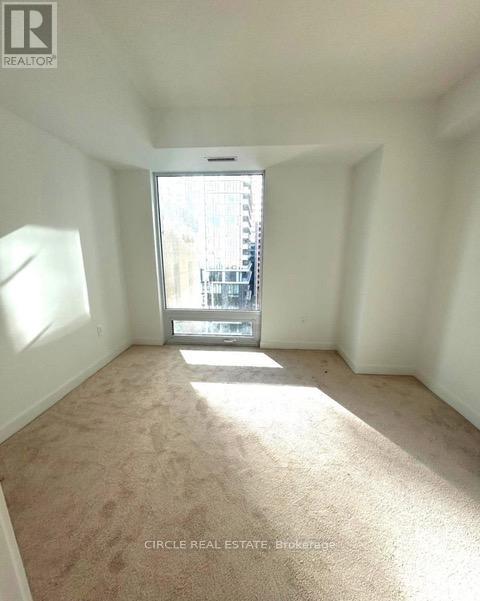 A carpeted room with a window and a view of a street outside.