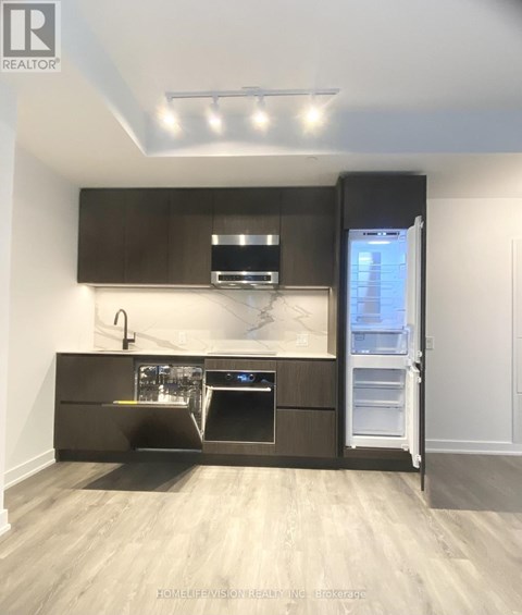 A modern kitchen with dark brown cabinets and stainless steel appliances.