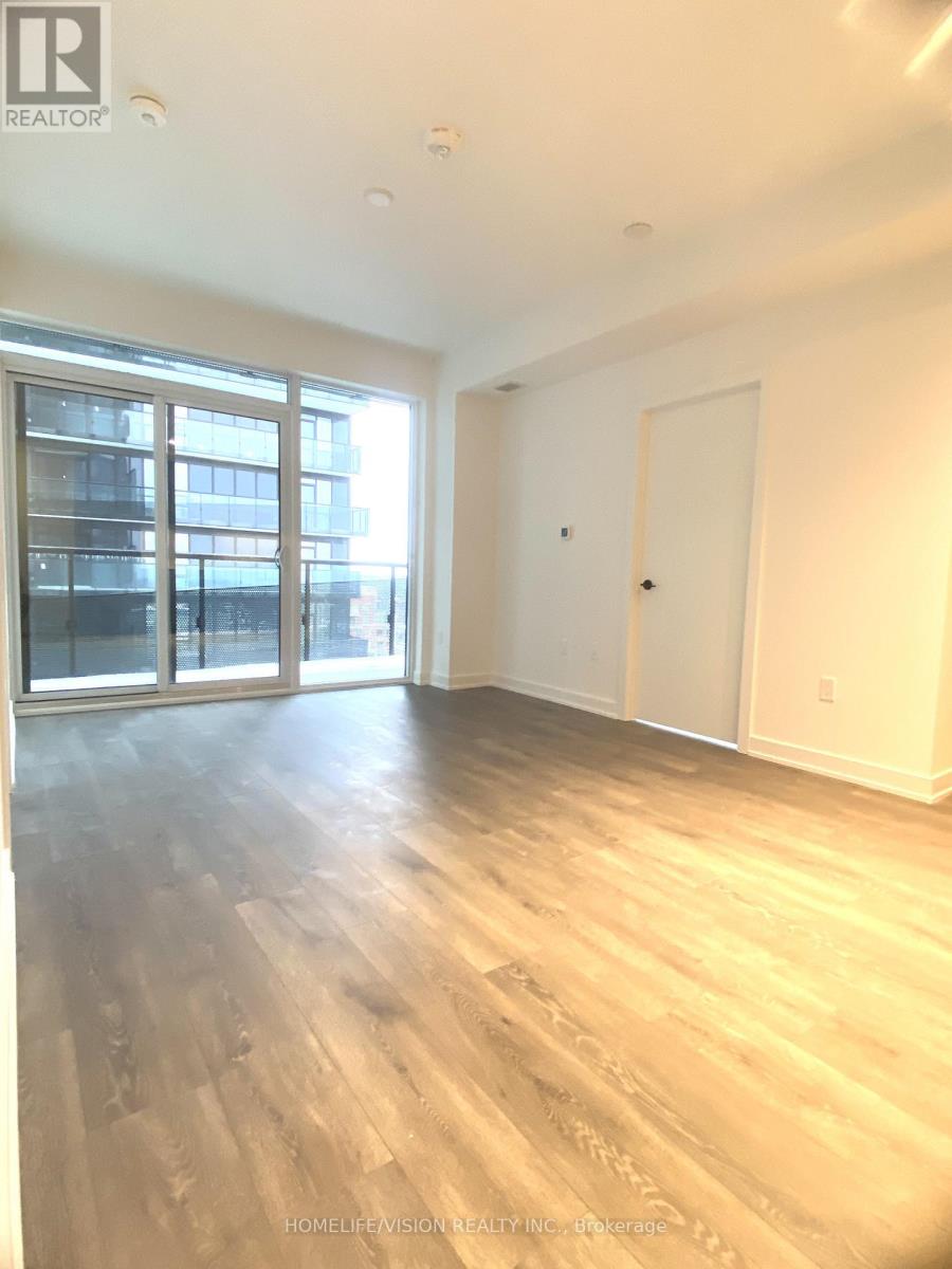 A spacious room with wooden flooring and a large window.