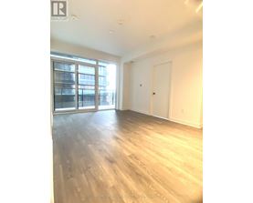 A spacious room with wooden flooring and a large window.