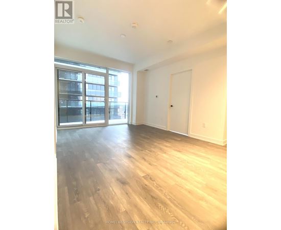 A spacious room with wooden flooring and a large window.