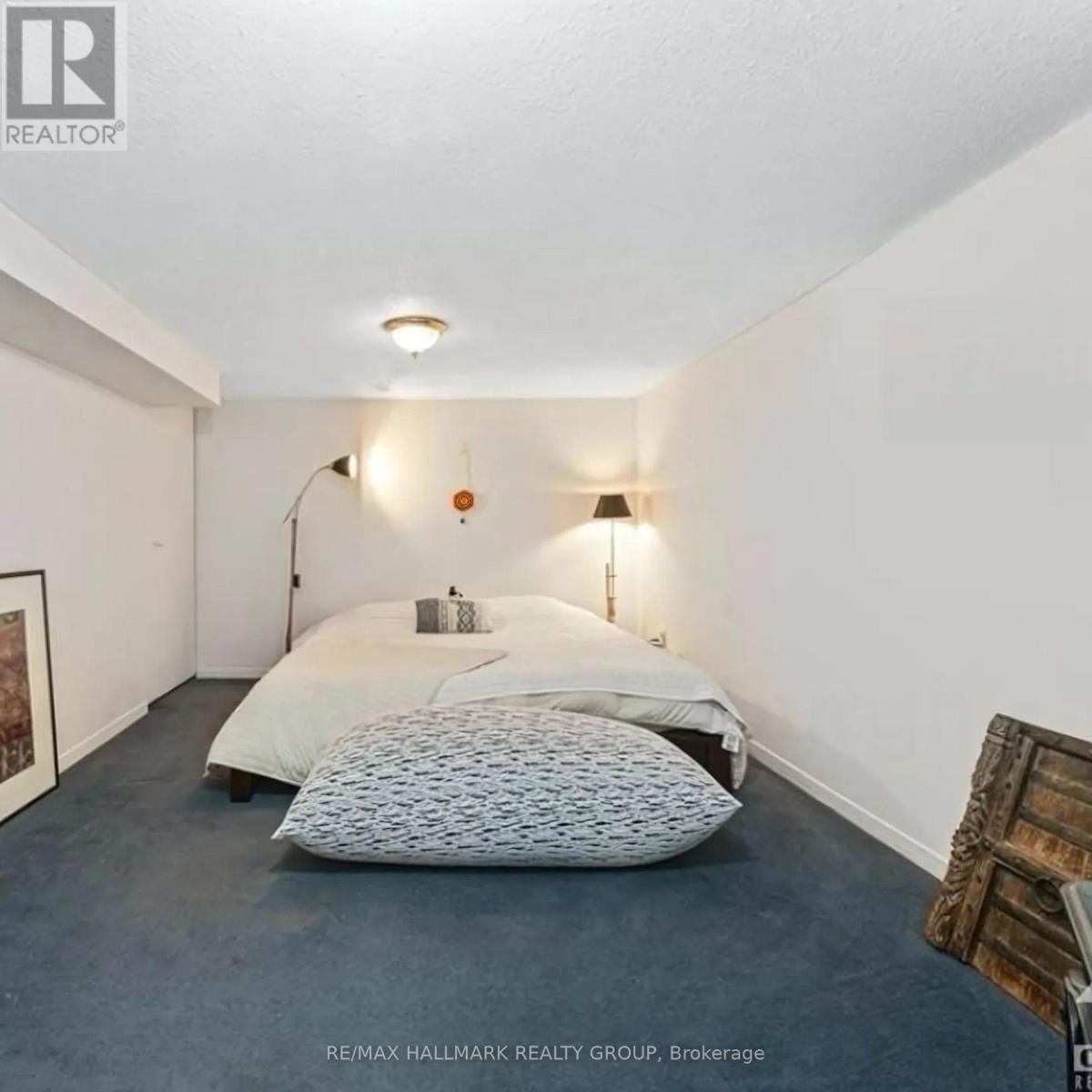 A bedroom with a bed, two pillows, a lamp, and a picture on the wall.