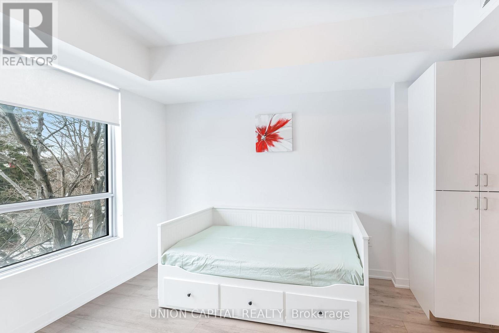 A white bedroom with a bed, wardrobe and a window.