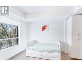 A white bedroom with a bed, wardrobe and a window.