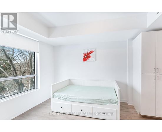 A white bedroom with a bed, wardrobe and a window.