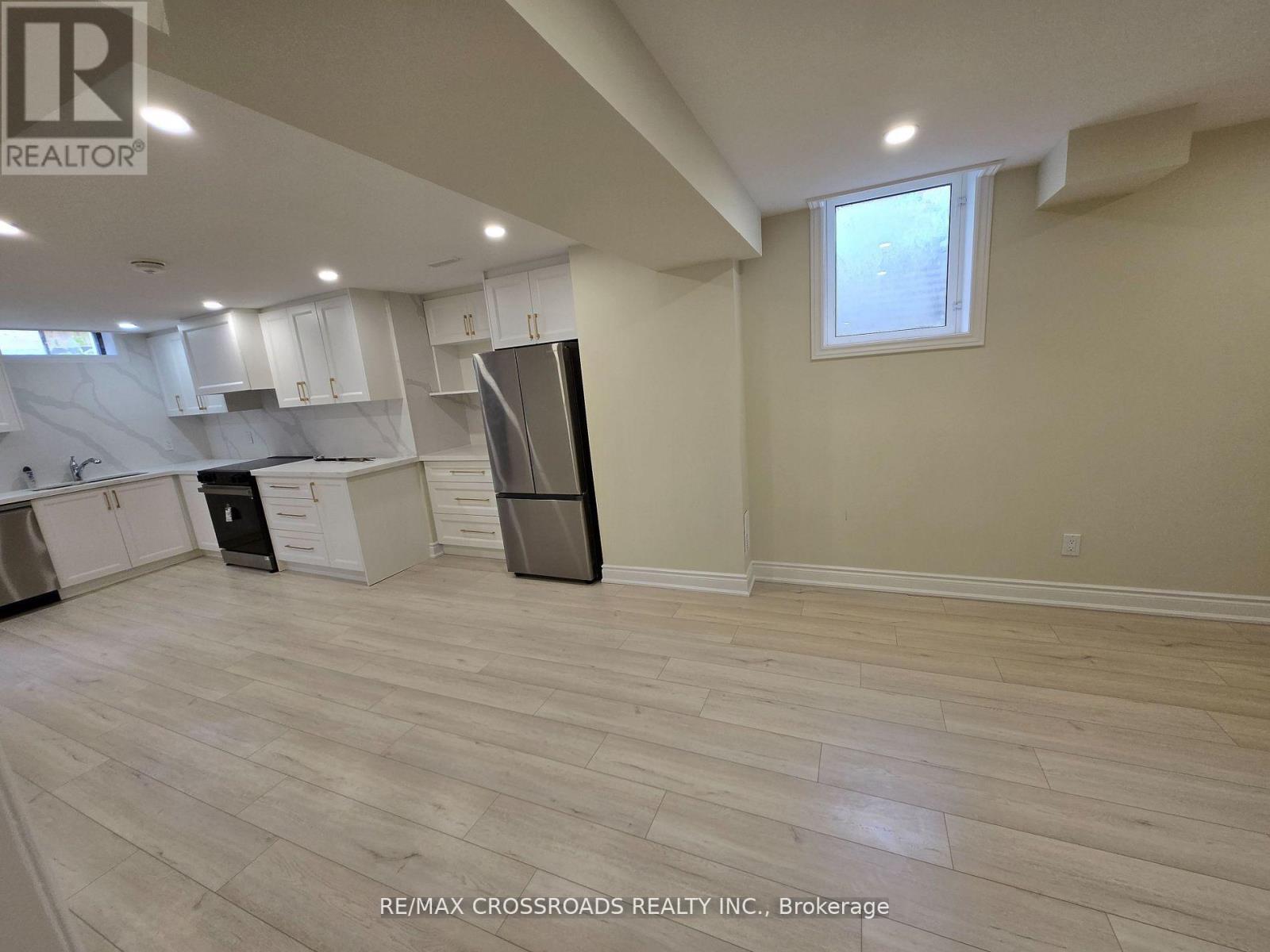 A kitchen with white cabinets and a black refrigerator.