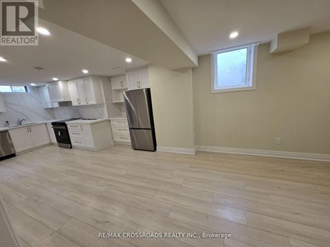 A kitchen with white cabinets and a black refrigerator.