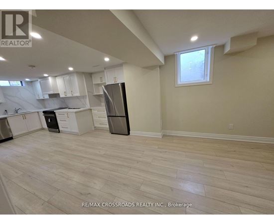 A kitchen with white cabinets and a black refrigerator.