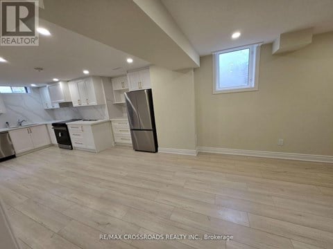 A kitchen with white cabinets and a black refrigerator.