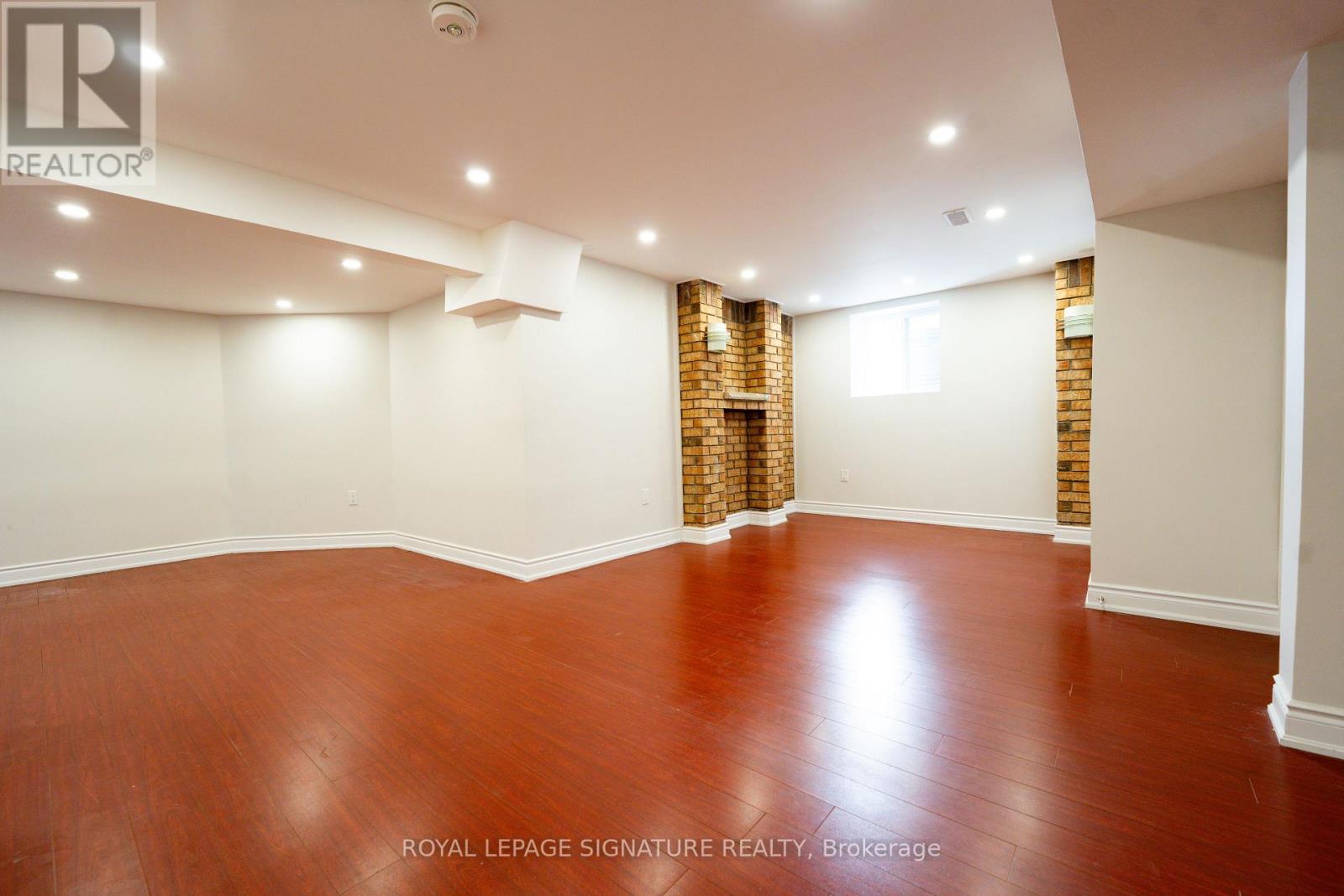 A room with wooden flooring and a brick wall in the corner.
