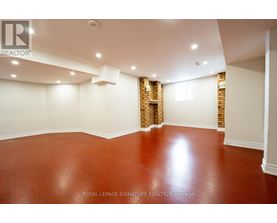 A room with wooden flooring and a brick wall in the corner.