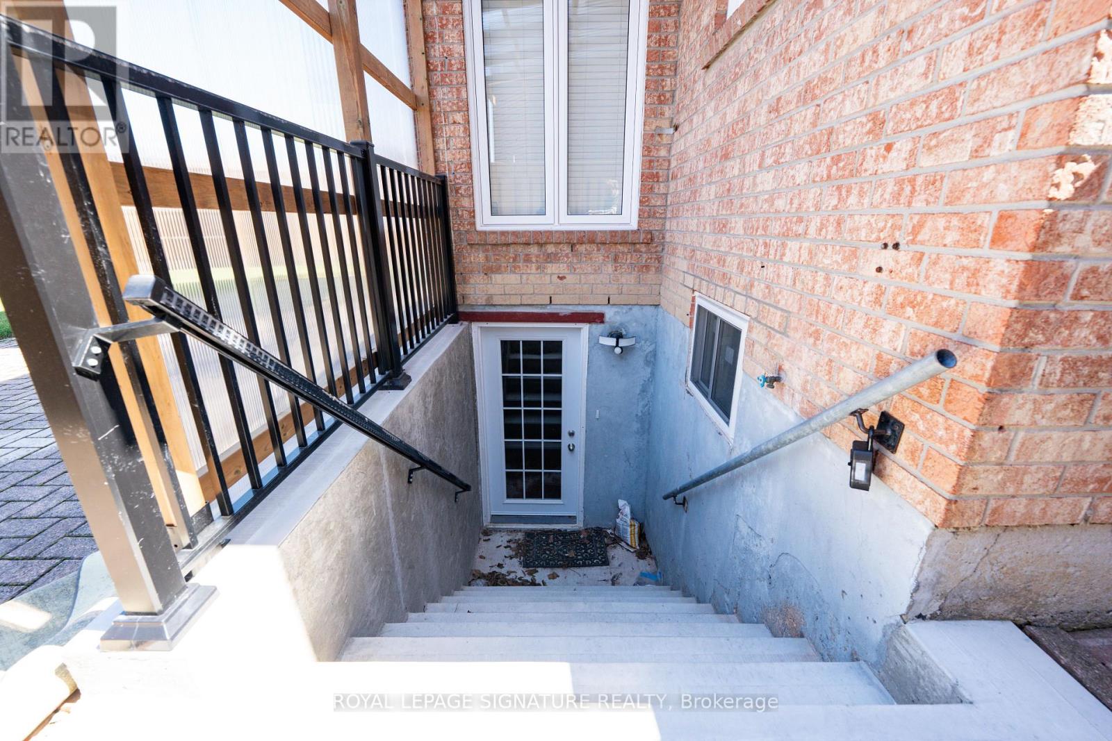 A staircase with a metal railing leads to a door in a brick building.