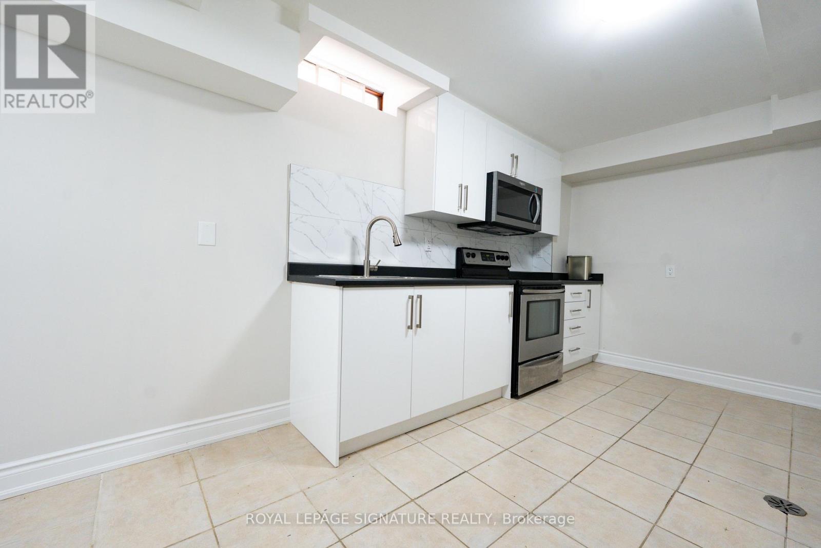 A kitchen with white cabinets and black appliances.