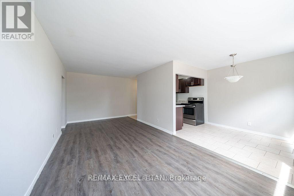 A spacious room with a grey floor and white walls, featuring a built-in kitchen area with a stove and cabinets.