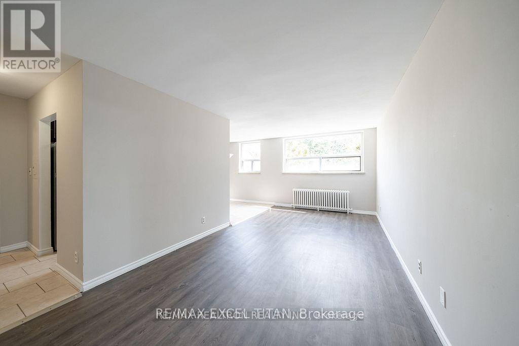 A spacious empty room with a window and radiator.